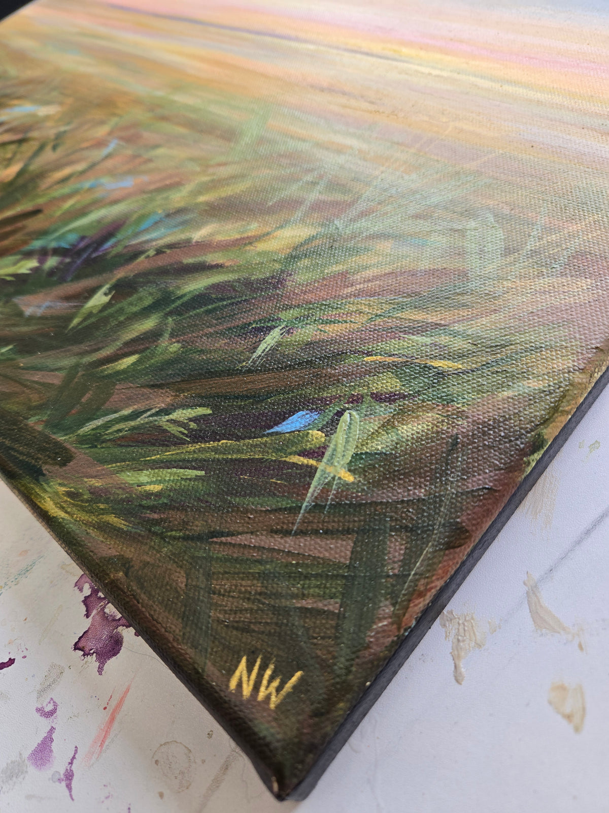 Close-up of a painting with green and brown hues on a textured surface.